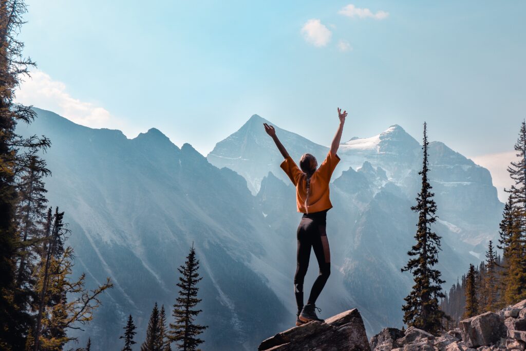 Woman on top of the mountain, reaching up in the air